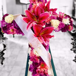 Pink and white floral standing arrangement on an easel with a ribbon sash