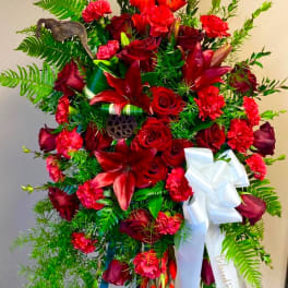 Large red floral standing spray with a white ribbon on an easel