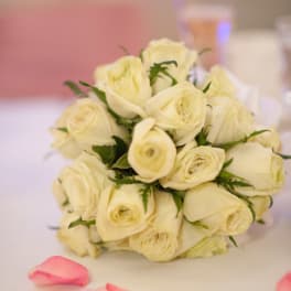 Bouquet of cream roses with pink petals scattered nearby