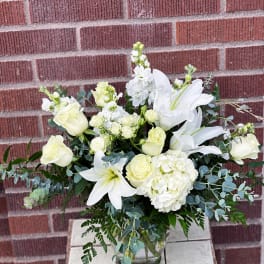 White roses and lilies arranged in a glass vase