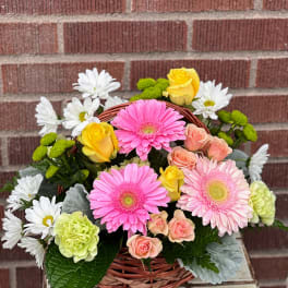 Basket arrangement with pink gerbera daisies, roses, and white daisies
