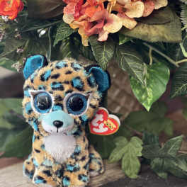 Plush leopard toy in front of an orange floral arrangement