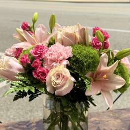 Pink roses and lilies arranged in a clear glass vase