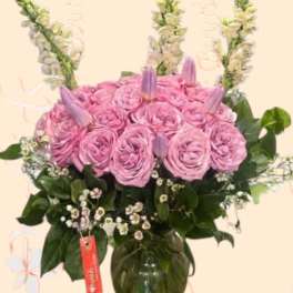 Pink rose arrangement in a glass vase with tall white flower spikes