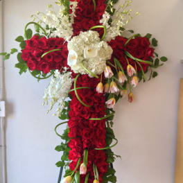 Large cross-shaped floral spray with red roses, white orchids, and calla lilies