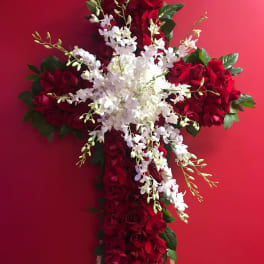 Cross-shaped floral arrangement of red roses and white orchids on an easel