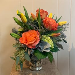 Orange roses and yellow tulips in a silver vase