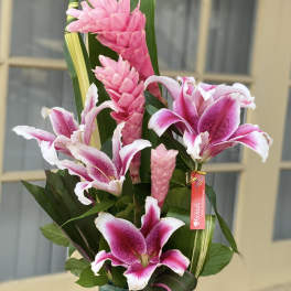 Pink lilies and tropical blooms in a glass vase
