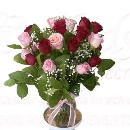 Bouquet of red and pink roses in a glass vase with a pink ribbon