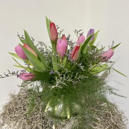 Pink and purple tulips in a glass vase with airy filler