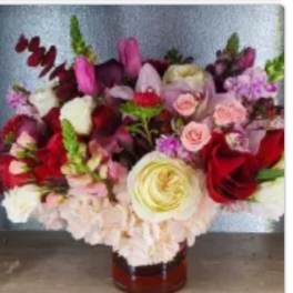 Mixed bouquet of roses and other blooms in a glass vase