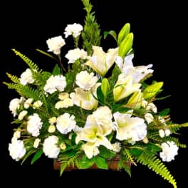 White lilies and carnations arranged in a wooden container