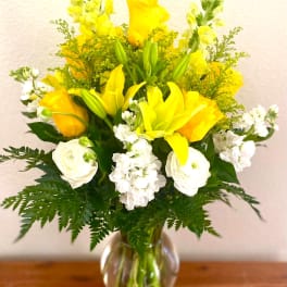 Yellow and white floral arrangement in a clear glass vase