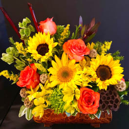 Bright bouquet with sunflowers and orange roses in a carved wooden container