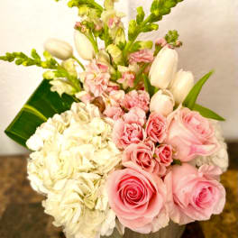 Pink roses and white hydrangeas in a low vase with tulips and snapdragons