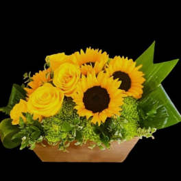 Yellow roses and sunflowers in a low rectangular container