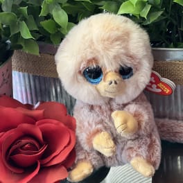 Stuffed monkey beside a red rose in a gift box