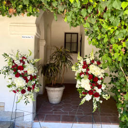Two standing floral sprays with red and white flowers on metal easels