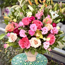 Pink and peach roses arranged in a vase with mixed greenery