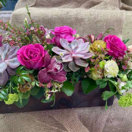 Pink roses and succulents arranged in a wooden box