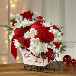 Red and white floral arrangement in a decorative sleigh container