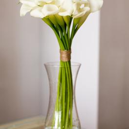 Tall bouquet of white calla lilies in a clear glass vase
