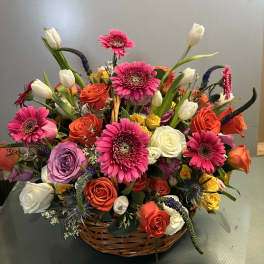 Mixed bouquet in a wicker basket with pink gerberas, roses, and white tulips