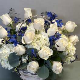 White roses and blue flowers in a white basket