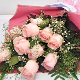 Bouquet of pale pink roses with baby's breath in pink wrapping