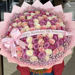 Large bouquet of pink, lavender, and white roses with a pink ribbon