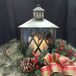 Holiday lantern centerpiece with pinecones, berries, and a plaid ribbon