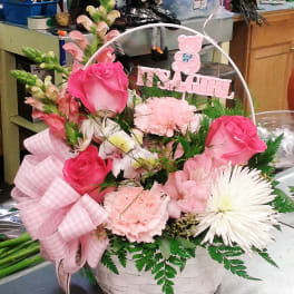 Pink and white flower basket with a ribbon and "It's a Girl" sign