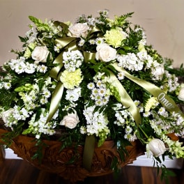 Large white floral casket spray with green ribbon