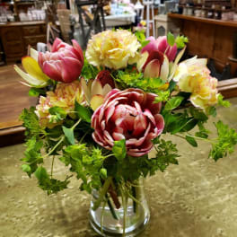 Mixed bouquet of pink and cream flowers in a clear glass vase