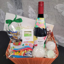 Gift basket with wine, candy, a glass, and bath items