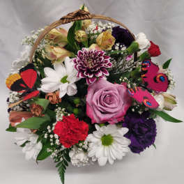 Basket arrangement with mixed flowers and colorful butterfly decorations