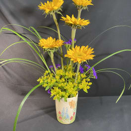 Yellow sunflowers in a decorated ceramic vase with purple filler flowers
