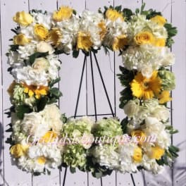 Square floral wreath with white and yellow flowers on a black stand