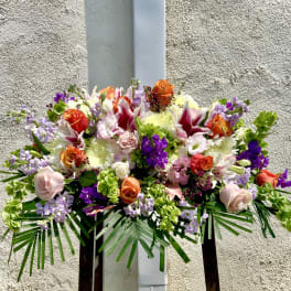 Large mixed floral arrangement with roses, lilies, and purple accents