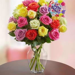 Colorful rose bouquet in a clear glass vase with a birthday balloon