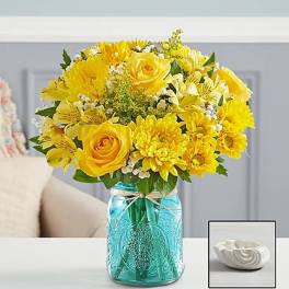 Yellow bouquet in a blue glass mason jar with a small white dish beside it