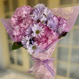 Pink and lavender bouquet wrapped in patterned paper with a ribbon