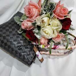 Bouquet of pink, white, and red roses with silver foliage in a black wrap