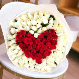 Heart-shaped bouquet of red and white roses wrapped in white paper
