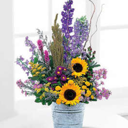 Mixed bouquet with sunflowers and purple flowers in a metal bucket