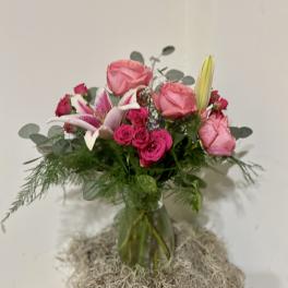 Pink roses and lilies arranged in a glass vase