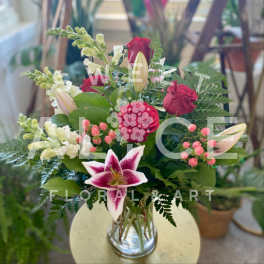 Bouquet of red roses and pink lilies in a clear glass vase