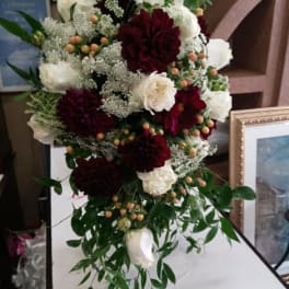 Tall bouquet of white and burgundy flowers with trailing greenery