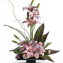 Pink lilies and roses arranged in a low black container with tall stems