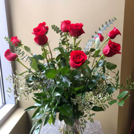 Tall bouquet of red roses in a clear glass vase